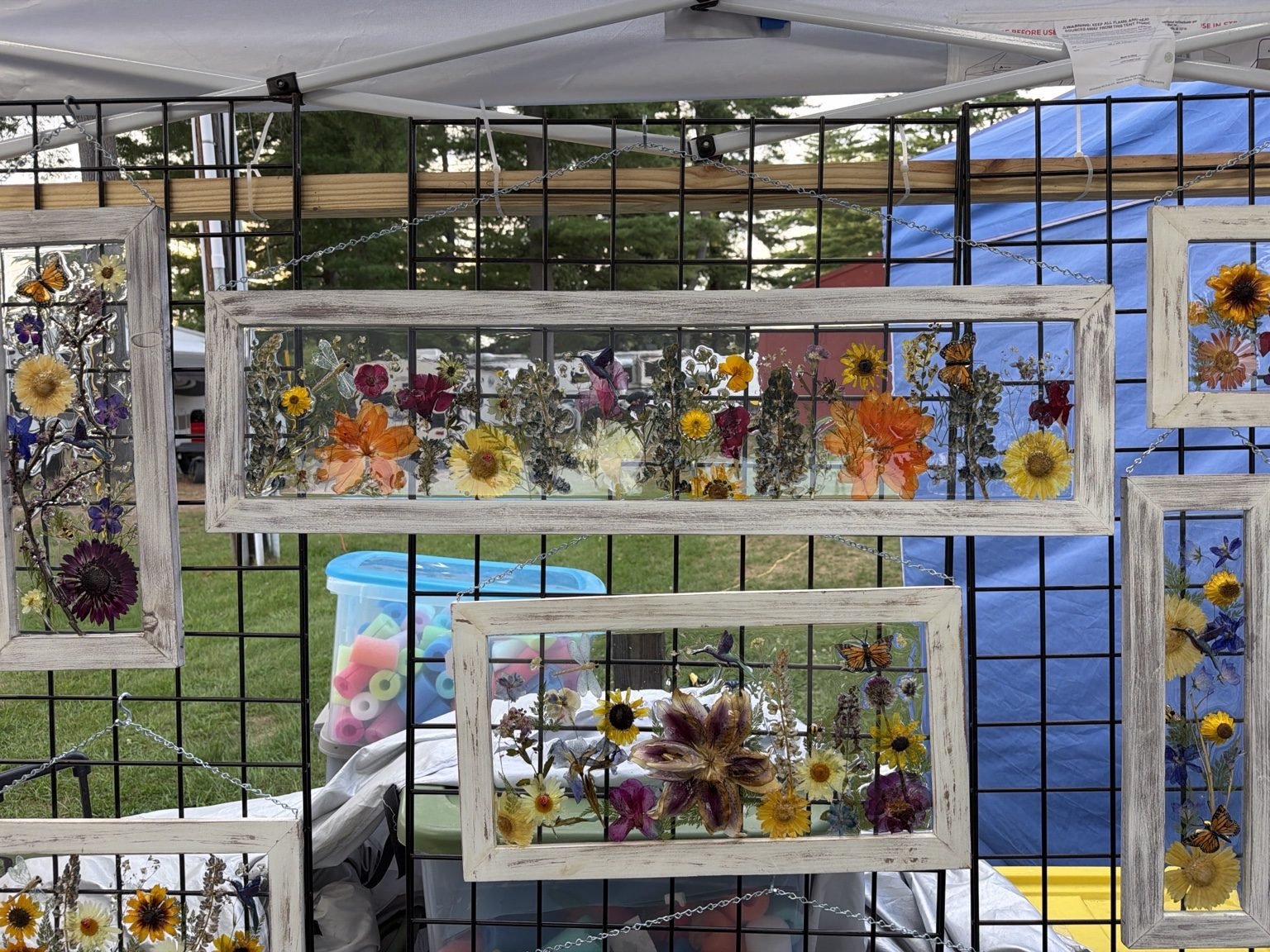 Display of multiple Snowbird Creations dimensional frames hanging at a craft fair booth